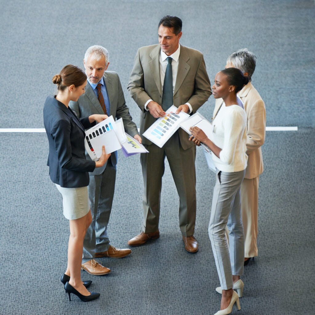 SEO Group of business professionals discussing charts and reports in a corporate setting.