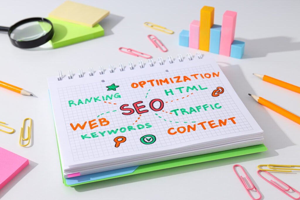 SEO Notepad with seo concepts and keywords surrounded by office supplies.